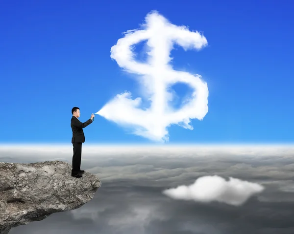 Uomo d'affari spruzzando dollaro segno forma nuvola vernice sulla scogliera — Foto Stock
