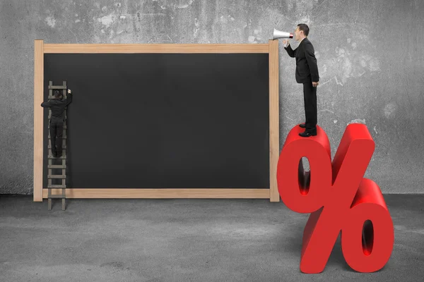 Sales man using megaphone on red percentage sign with blackboard — Stock Photo, Image