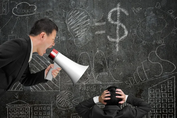 Boss using megaphone yelling at his employee with doodles wall — Stock Photo, Image