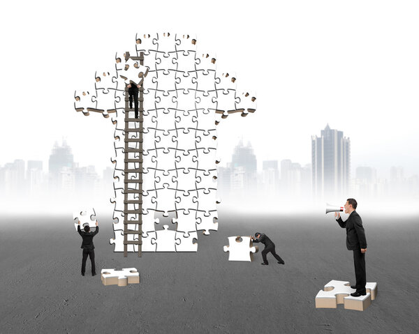 Businessman commanding workers to build arrow jigsaw puzzle with