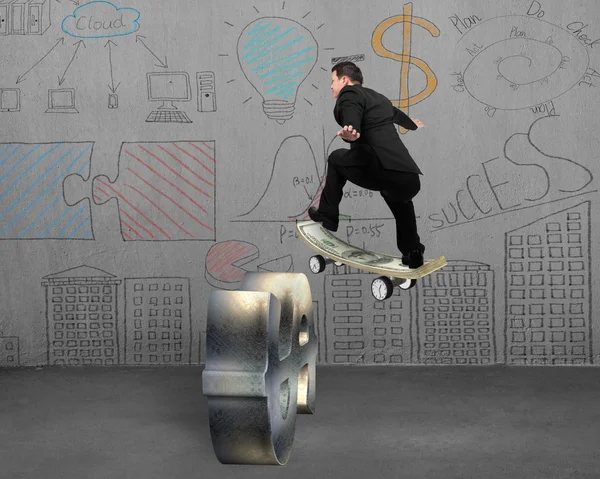 Businessman skating on money skateboard across metal dollar sign — Stock fotografie