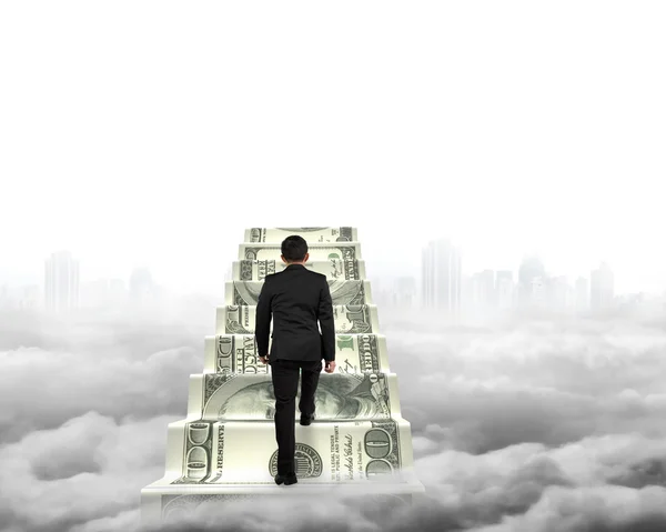 Businessman climbing the money stairs with gray cityscape clouds — Stock Photo, Image