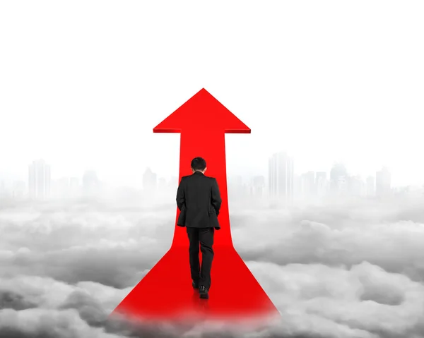 Businessman walking on red arrow sign path with cityscape clouds — Stock Photo, Image