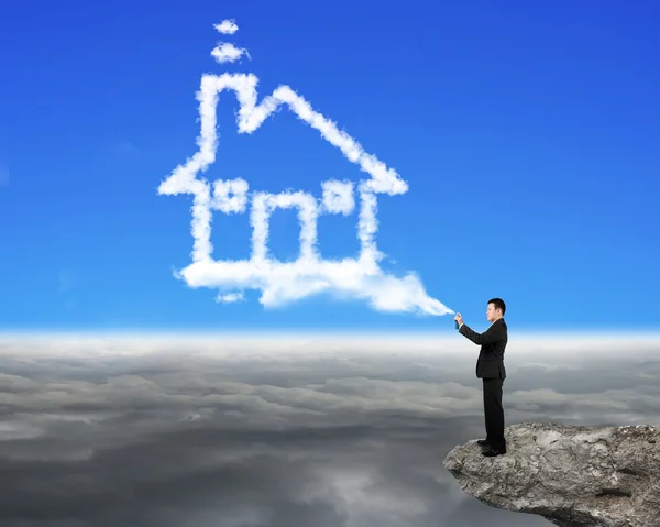 Businessman spraying house shape cloud paint on the cliff — Stock Photo, Image