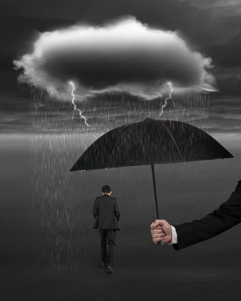 Hand holding umbrella protecting businessman from dark cloud rai Royalty Free Stock Photos