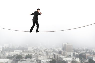 Businessman balancing and walking on the rope with urban scene