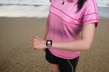 Sport woman wearing smartwatch with health sensor on beach backg