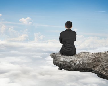 Rear view businessman sitting on cliff with natural sky cloudsca