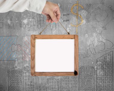 Hand holding blank white message board with business doodles wal