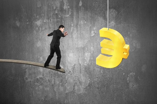 Businessman balancing on wooden board with golden euro symbol — Stockfoto