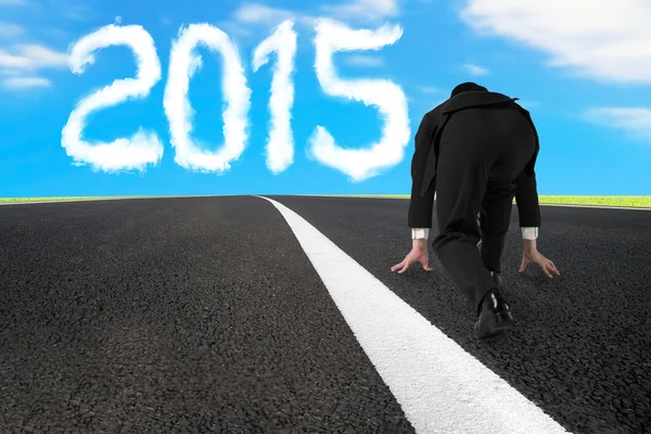 Businessman ready to run on asphalt road with 2015 cloud — Stockfoto