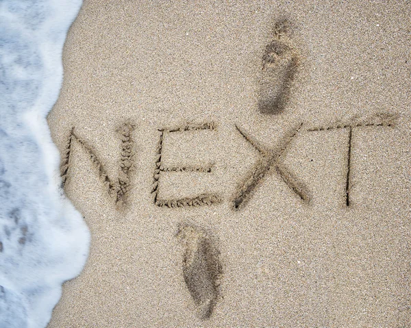 NEXT and footprints on the sand beach with wave foam — Stock Photo, Image