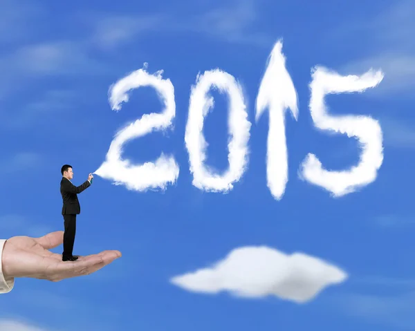 Hand holding businessman spraying 2015 arrow up clouds with sky — Stok fotoğraf
