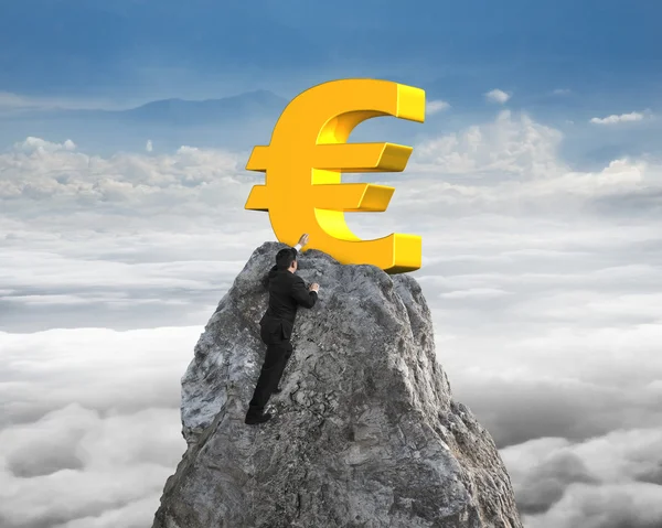 Businessman hand wanting for euro symbol on peak with cloudscape — Zdjęcie stockowe