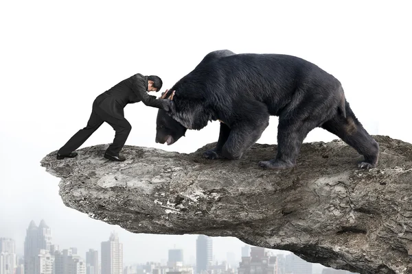 Businessman fighting against black bear on cliff with sky citysc — Stockfoto