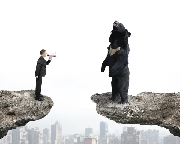 Businessman yelling at black bear on cliff with cityscape — Stockfoto