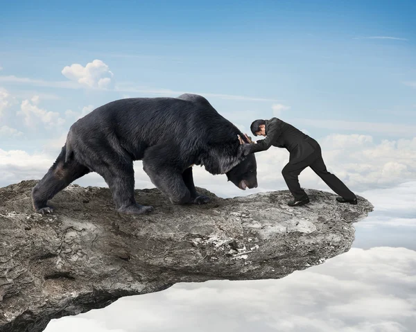 Businessman fighting against black bear on cliff with sky clouds — Φωτογραφία Αρχείου