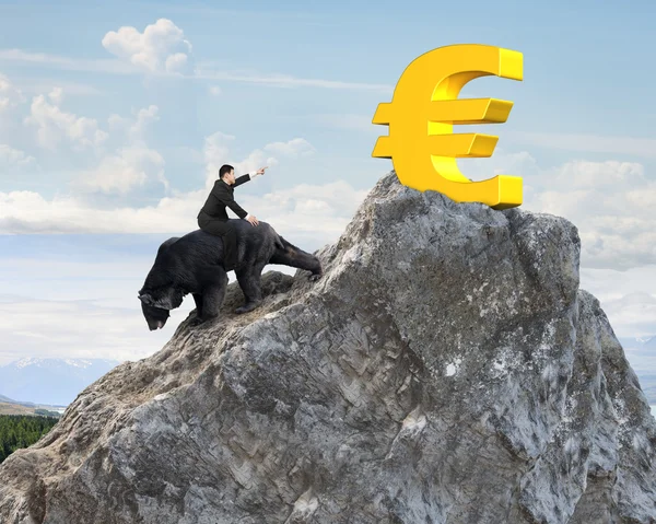 Businessman riding bear pursuing gold euro symbol on mountain pe — Zdjęcie stockowe