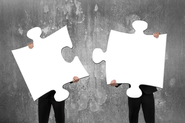 Two business people assembling white jigsaw puzzles with concret Stock Obrázky