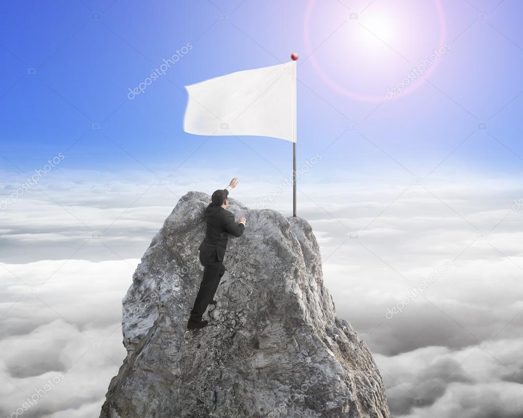 Businessman hand wanting for white flag on peak with sunlight