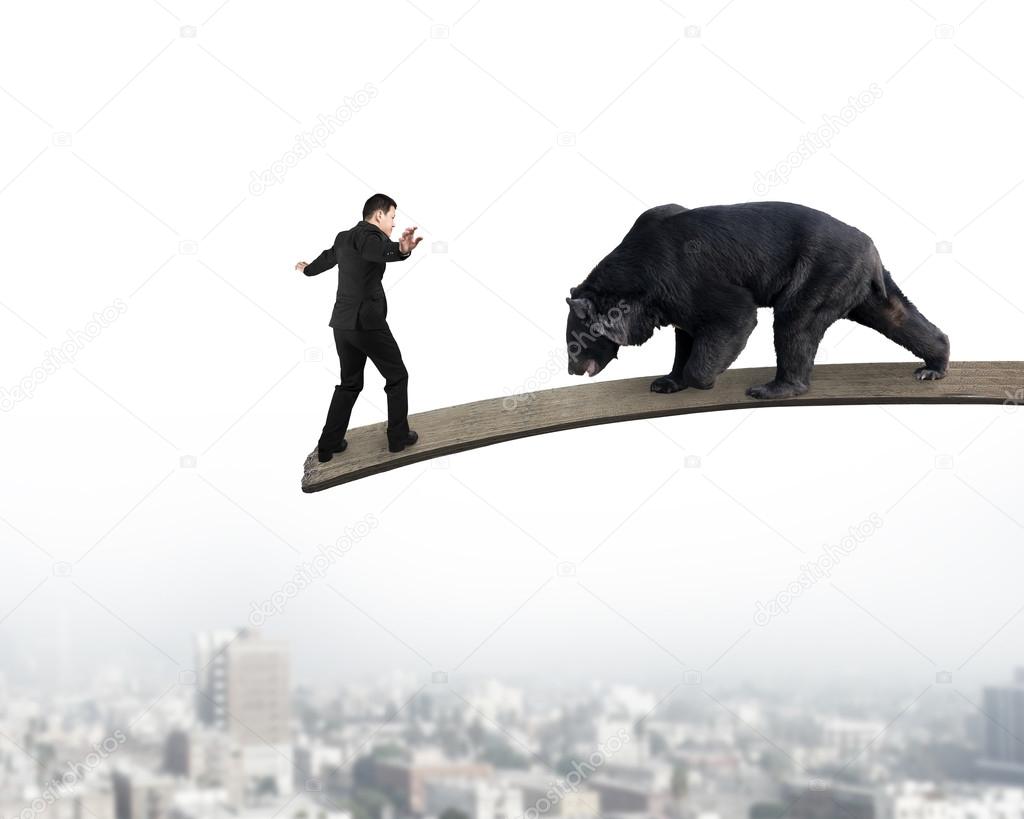 Businessman against black bear balancing on wooden board with ci