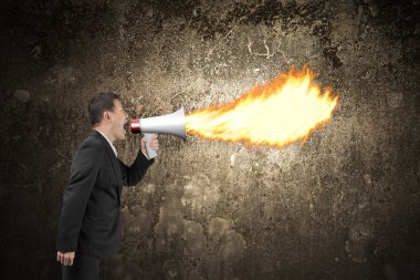 Angry businessman screaming into megaphone spitting fire illumin