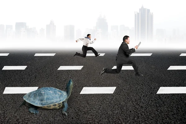 Two businessmen running with turtle on asphalt road — Stock Photo, Image