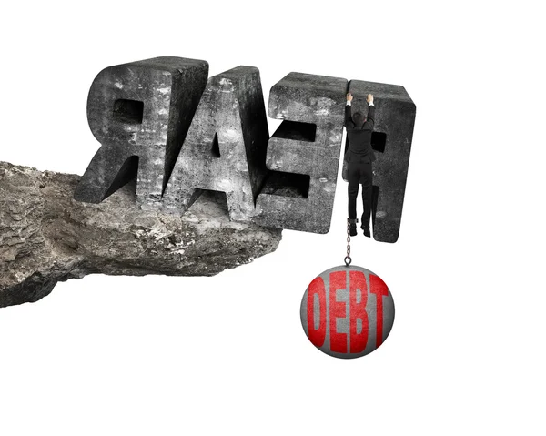 Man shackled by debt ball hanging fear word edge cliff — Stok fotoğraf