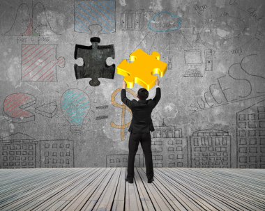 Businessman inserting gold jigsaw puzzle piece into the dark hol
