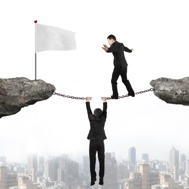 Businessman balancing on cracking chain another man holding towa