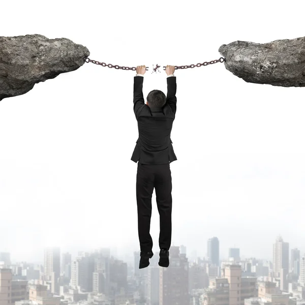 Businessman hand hanging broken rusty iron chains connect two cl