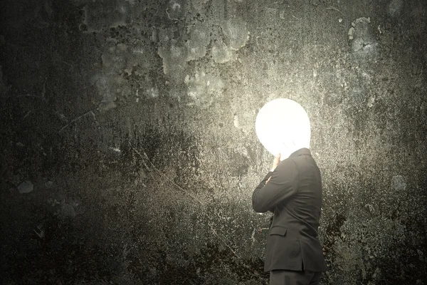 Thinking businessman with lamp head illuminated dark mottled con — Stock fotografie