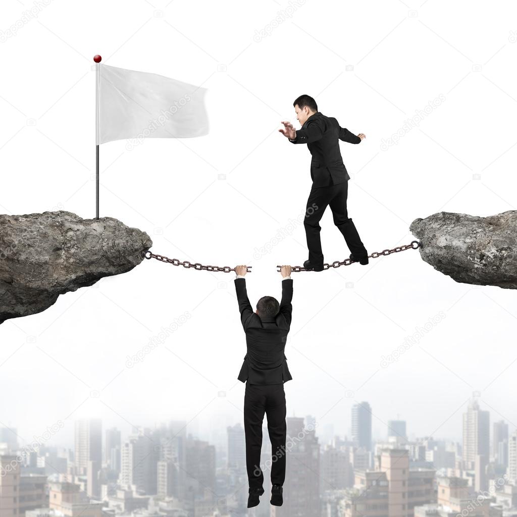 Businessman balancing on cracking chain another man holding towa