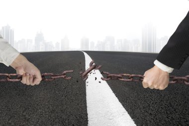 Businessman pulling rusty iron chains broken with asphalt road c