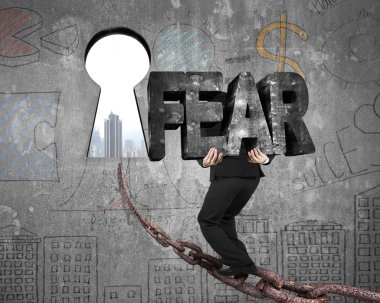 Man carrying fear word on chain toward keyhole with cityscape