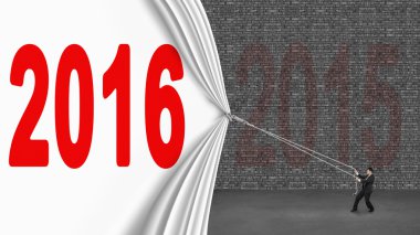 Businessman pulling down 2016 curtain covering old 2015 brick wa