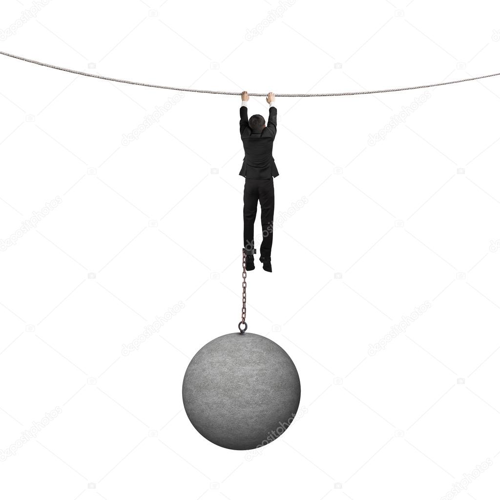 Businessman shackled by heavy concrete ball hanging on the rope