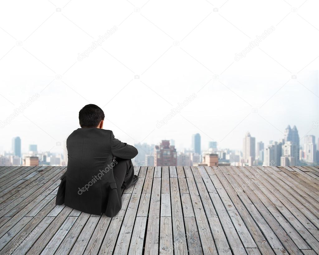 Rear view businessman hands holding knee sitting with urban scen
