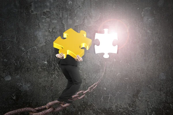 Businessman carrying gold jigsaw puzzle piece toward hole with s — Stockfoto