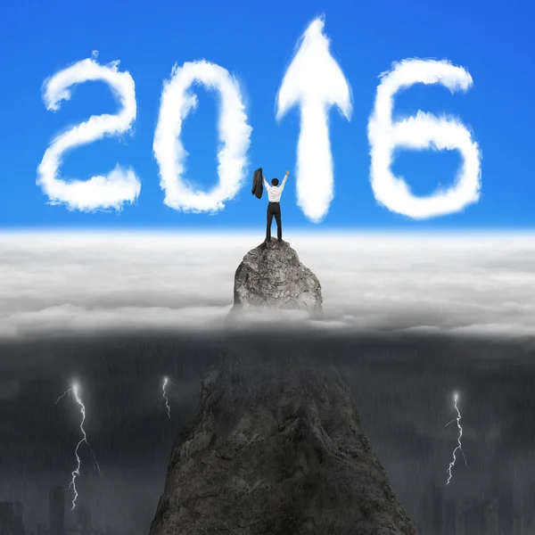 Businessman cheering on mountain peak for 2016 arrow sign clouds — 图库照片