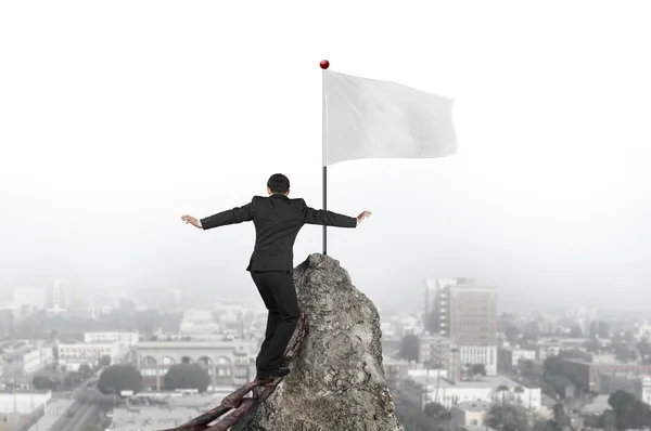 Businessman walking on iron chain toward white flag with citysca — Φωτογραφία Αρχείου