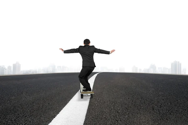 Businessman skateboarding on asphalt road with urban scene — Stockfoto