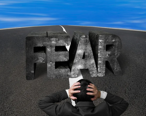 Businessman holding head facing fear concrete word on asphalt ro
