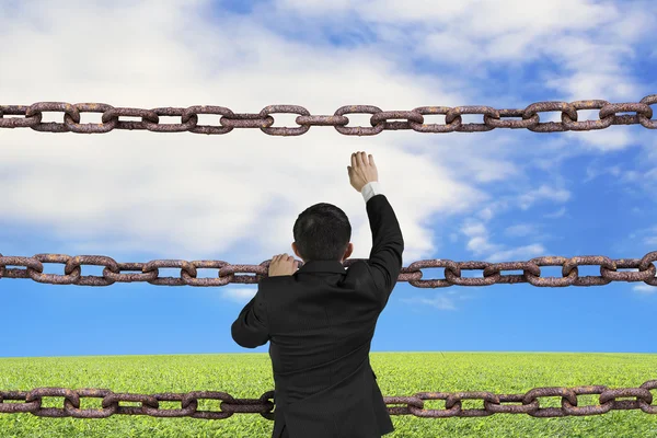 Businessman climbing on iron chains with natural sky clouds gras — Stock Photo, Image