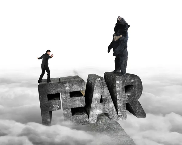 Businessman against bear balancing on fear 3D word with cloudy — Zdjęcie stockowe