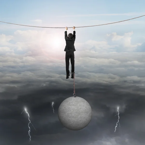 Homme d'affaires enchaîné par une boule de béton accrochée à une corde avec ciel — Photo