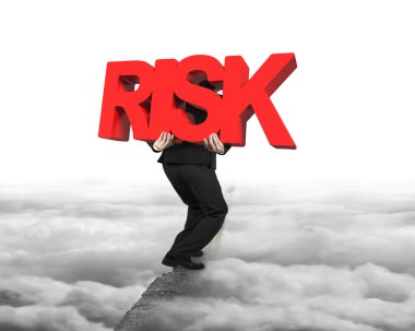 Man carrying red RISK word on ridge with cloudscape cityscape