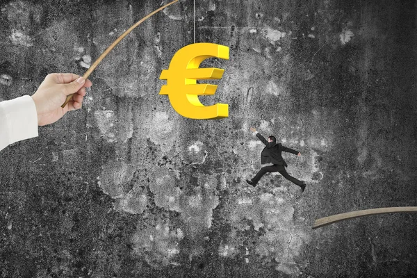 Man jumping golden euro symbol fishing lure mottled concrete wal — Stockfoto