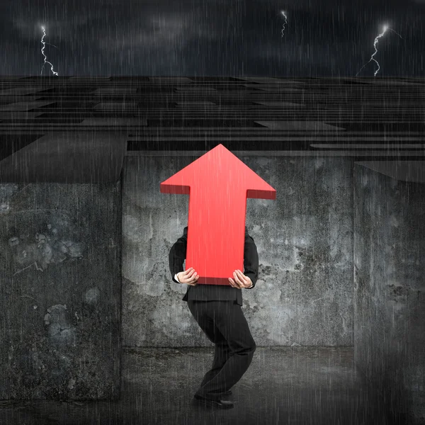 Man carrying red arrow up sign entering maze with dark — Stockfoto