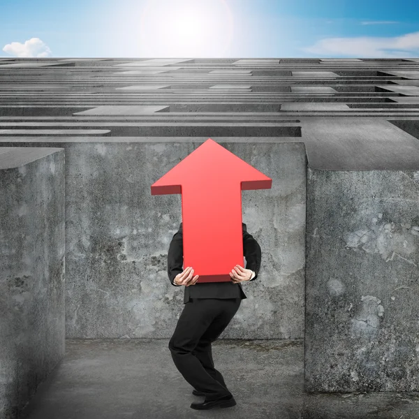 Man carrying red arrow up sign entering maze with sky — Stock Photo, Image